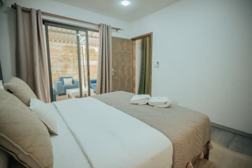 Spacious bedroom at Gerards & Angel villa in Pereybere with pool view, white bedding, and sitting area access