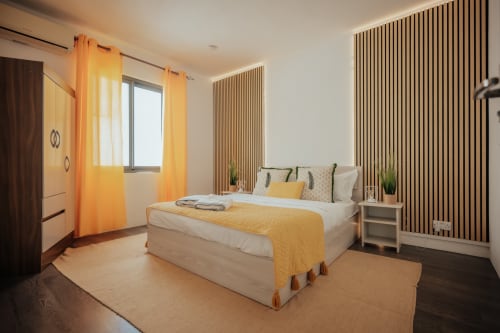 Modern bedroom at Gerards & Angel villa in Pereybere with yellow accents, wooden slat feature wall, and pool view window.