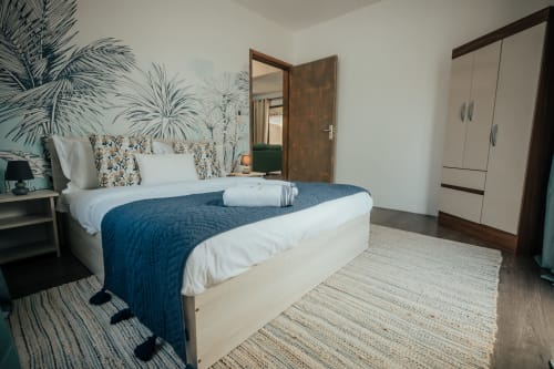 Modern bedroom at Gerards & Angel villa in Pereybere with blue bed, tropical wall art, and wardrobe.
