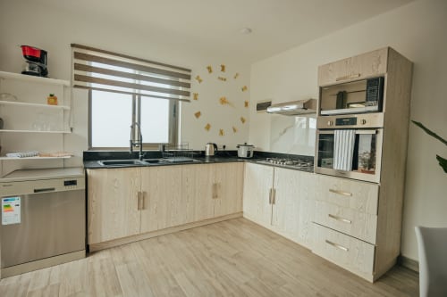 Modern kitchen in Summer of Hope villa at Gerards & Angel, Pereybere, with light wood cabinets and black countertops