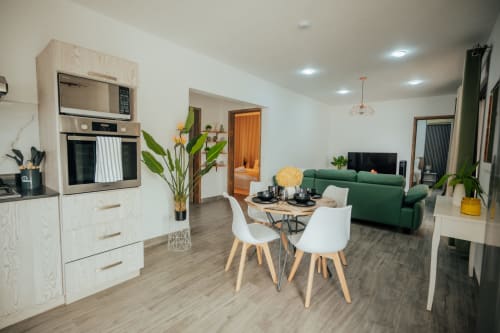 Modern open-plan villa at Gerards & Angel, Pereybere with white kitchen, green sofa, and dining area with plants