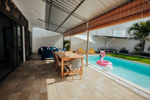 Covered terrace at Gerards & Angel villa in Pereybere with dining table, blue sofa, and turquoise pool with flamingo float