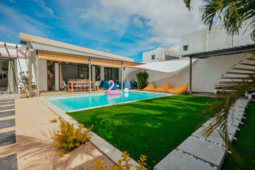 Modern villa with turquoise pool, green lawn, and lounge chairs at Gerards & Angel, Pereybere