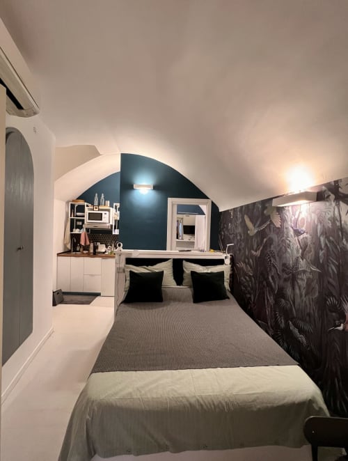 Cozy attic bedroom at Buonanotte Colosseo Rome with arched ceiling, dark accent wall, and kitchenette