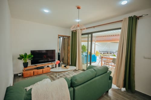 Modern villa living room at Gerards & Angel in Pereybere with green sofa, TV, and pool view terrace