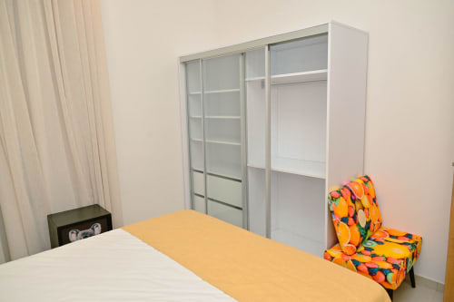 Chambre moderne chez Gerards & Angel avec penderie vitrée coulissante, lit blanc, coussin coloré et vue sur l'océan à Pointe aux