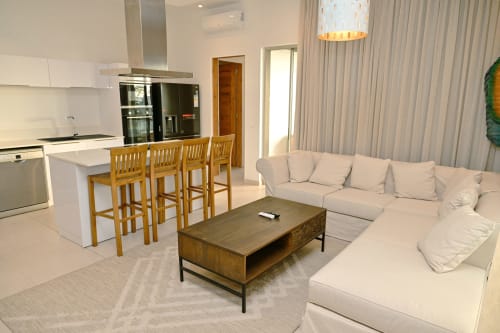 Séjour moderne et ouvert à l'appartement en bord de mer Gerards & Angel à Pointe aux Piments avec canapé crème, îlot de cuisine