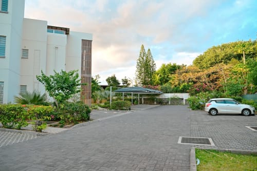 Immeuble blanc moderne avec entrée aménagée, parking et végétation tropicale à Gerards & Angel, Pointe