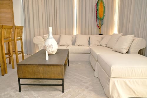 Salon de l'appartement en bord de mer Gerards & Angel avec canapé sectionnel crème, table basse en bois et rideaux offrant une vue océanique