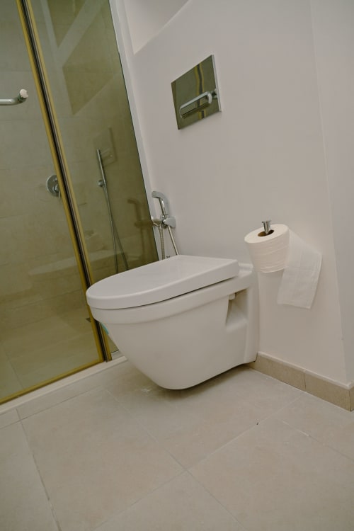 Toilettes murales blanches modernes avec porte-rouleau de papier toilette dans l'appartement Ocean Point Beachfront de Gerards & Angel, Pointe aux