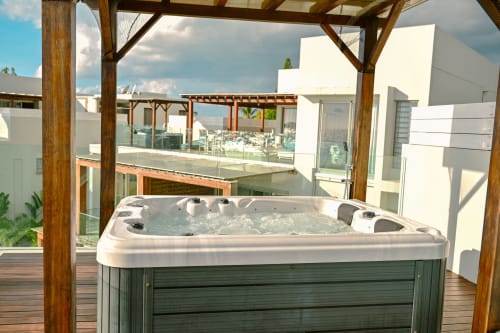 Luxueux bain à remous sur terrasse en bois de l'appartement en bord de mer Gerards & Angel à Pointe aux Piments avec vue océan