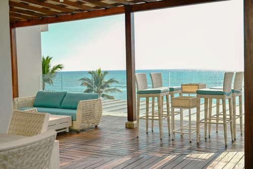 Terrasse en bord de mer à Gerards & Angel avec sièges en rotin, coussins turquoise et vue sur l'océan à l'Île Maurice