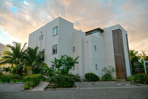 Immeuble blanc moderne à Gerards & Angel, Pointe aux Piments avec palmiers et cour pavée au coucher de soleil