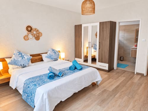 Spacious Ti Palmier bedroom at Gerards & Angel, Flic-en-Flac, with queen bed, blue accents, wardrobe, and ensuite bathroom
