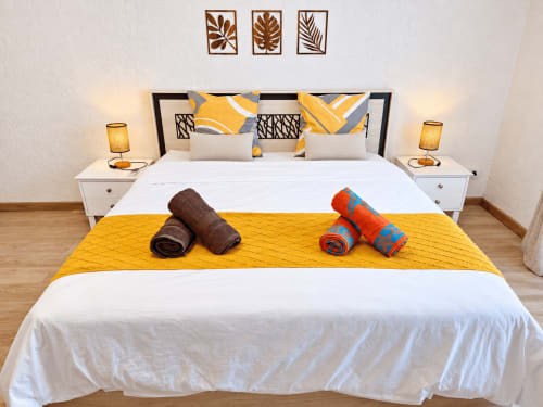 Modern bedroom at Ti Palmier apartment in Flic-en-Flac with queen bed, yellow accents, and welcome towels