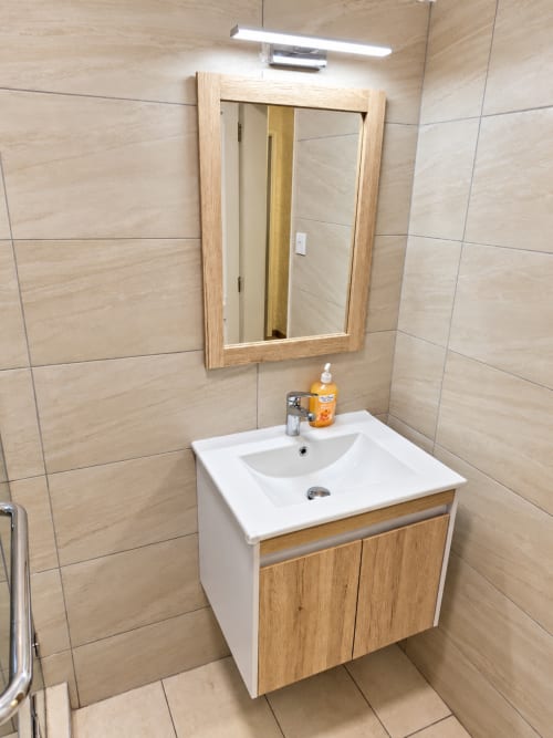 Modern bathroom at Gerards & Angel in Flic-en-Flac with wooden vanity, white sink, and tiled walls