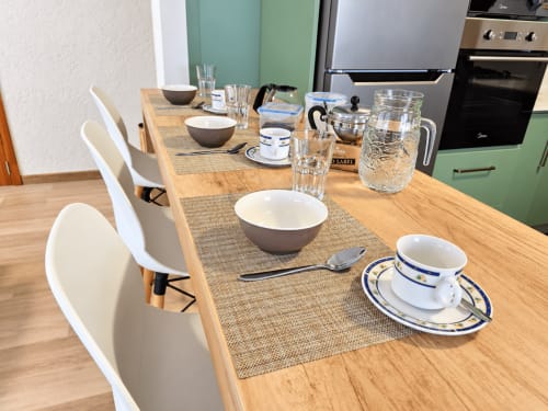 Modern dining table set at Gerards & Angel apartment in Flic-en-Flac with place settings, glasses, and green kitchen backdrop