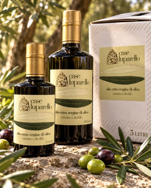 Bottiglie e confezioni di olio extravergine di oliva Case Luparello esposte con olive fresche a Noto, Sicilia