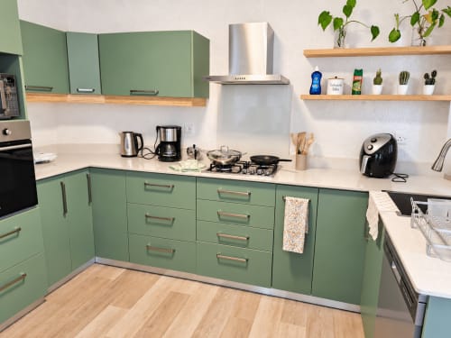 Modern green kitchen with white countertops, stainless steel appliances, and wooden shelves at Gerards & Angel, Flic-en-Flac