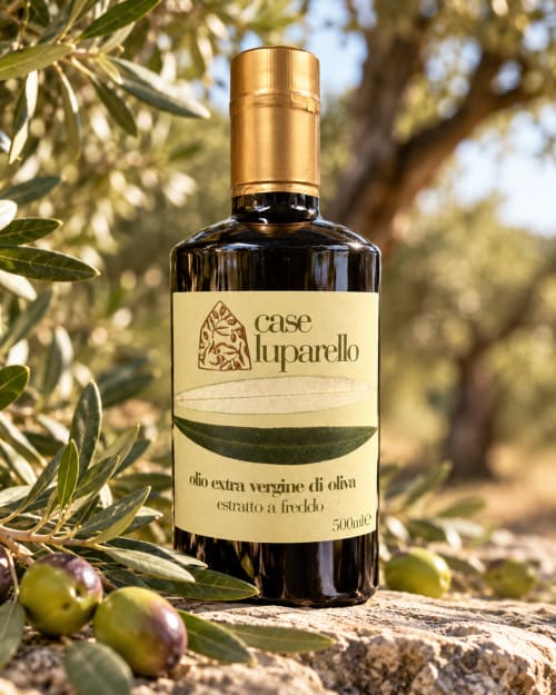 Bottiglia di olio extravergine di oliva Case Luparello con tappo dorato tra rami di ulivo a Noto, Sicilia