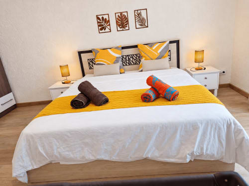 Bright bedroom at Gerards & Angel in Flic-en-Flac with white bed, yellow accent runner, rolled towels, and modern decor