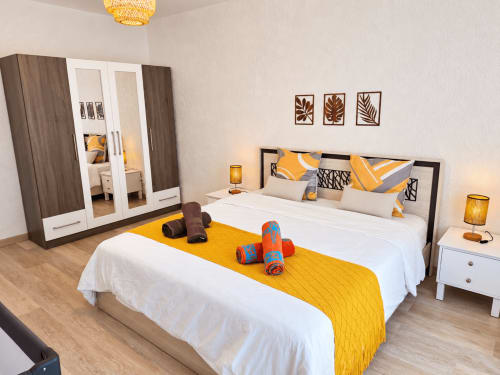 Modern bedroom at Ti Palmier apartment in Gerards & Angel, Flic-en-Flac with yellow accents, mirrored wardrobe, and pool