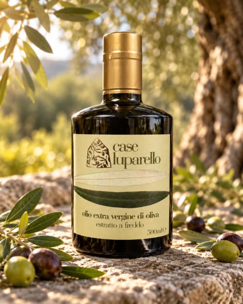 Bottiglia di olio extravergine di oliva Case Luparello esposta con olive fresche e rami di ulivo a Noto
