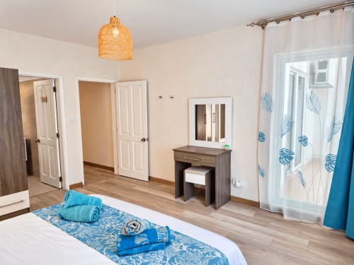 Bright bedroom at Gerards & Angel, Ti Palmier apartment in Flic-en-Flac with wooden vanity, blue accents, and glass doors to