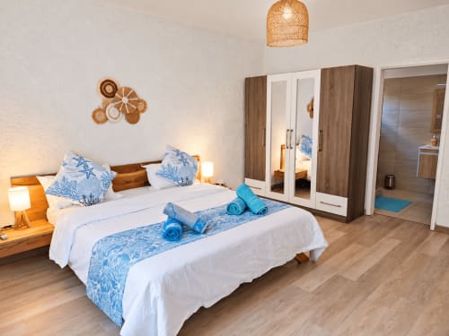Ti Palmier bedroom at Gerards & Angel in Flic-en-Flac with queen bed, blue accents, wooden wardrobe, and en-suite bathroom