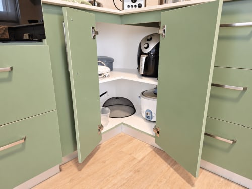 Open kitchen cabinet showing small appliances including coffee maker and rice cooker at Ti Palmier apartment, Gerards &