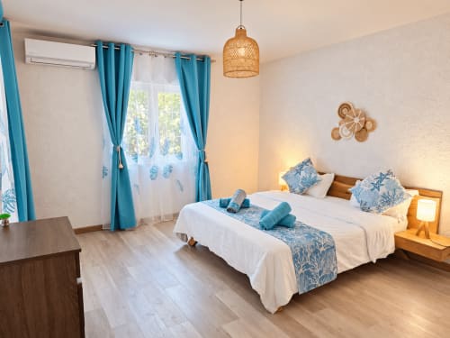Bright bedroom at Gerards & Angel in Flic-en-Flac with twin beds, turquoise curtains, woven pendant light, and wooden