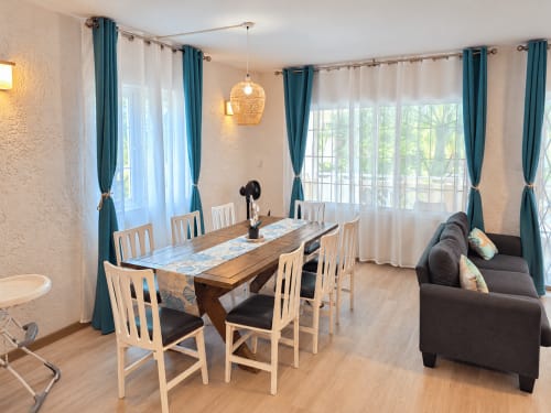 Bright dining area with wooden table, chairs, and dark sofa at Ti Palmier apartment in Flic-en-Flac, Mauritius, with teal