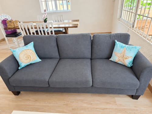 Gray upholstered sofa with turquoise coastal pillows in Ti Palmier apartment at Gerards & Angel, Flic-en-Flac