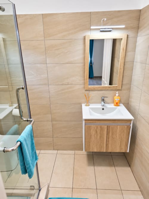 Modern bathroom at Gerards & Angel, Ti Palmier apartment in Flic-en-Flac with wooden vanity, mirror, and shower.