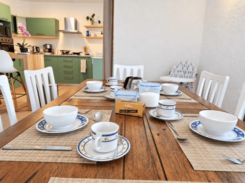 Dining table set for breakfast at Ti Palmier apartment, Gerards & Angel, Flic-en-Flac with white chairs and blue-trimmed