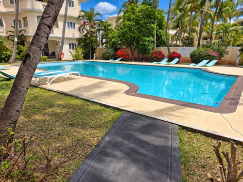 Sparkling pool at Gerards & Angel in Flic-en-Flac with loungers, palm trees, and tropical garden setting