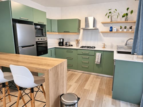 Modern kitchen with sage green cabinetry, wooden countertop island, stainless steel appliances at Ti Palmier apartment,