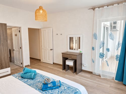 Spacious bedroom at Gerards & Angel, Ti Palmier apartment in Flic-en-Flac with modern furnishings, wooden desk, and balcony