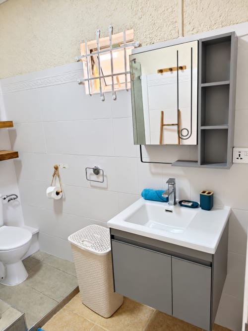 Modern bathroom with white tile walls, gray vanity, mirror cabinet, and blue towels at Gerards & Angel apartment in Flic en