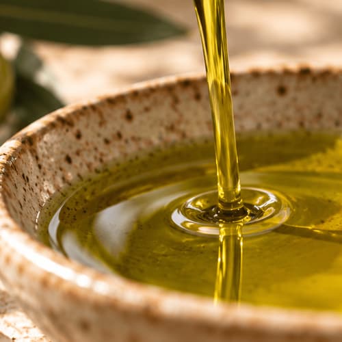 L'olio d'oliva dorato si versa in una rustica ciotola di ceramica a Case Luparello, Noto, Sicilia