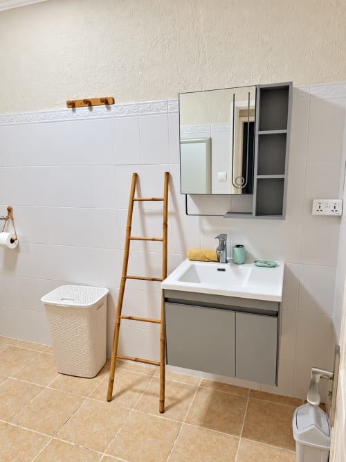 Modern bathroom with white tiles, vanity sink, mirror cabinet, and bamboo ladder at Gerards & Angel, Flic en Flac