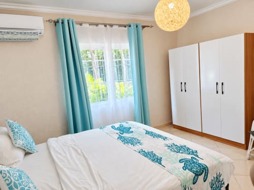 Bright bedroom with turquoise curtains, white wardrobe, and sea turtle bedding at Gerards & Angel, Flic en Flac