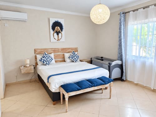 Bright bedroom at Gerards & Angel in Flic en Flac with wooden bed, blue accents, pendant light, and patio access