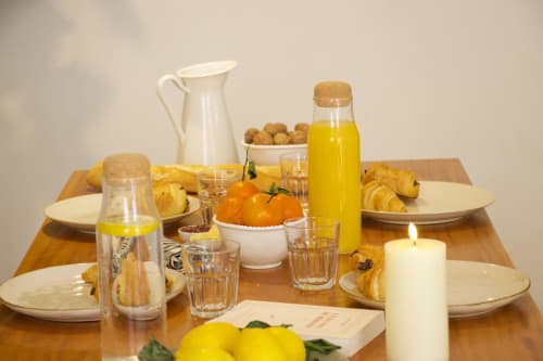Table de petit-déjeuner élégante à la villa Mi Casa Es Su Casa à Carcassonne avec viennoiseries fraiches, agrumes et produits locaux