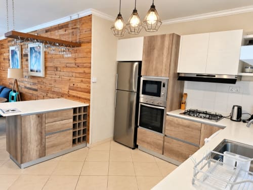 Modern kitchen with wooden cabinetry, stainless steel appliances, gas cooker, and island bench at Sirokann apartment in Flic