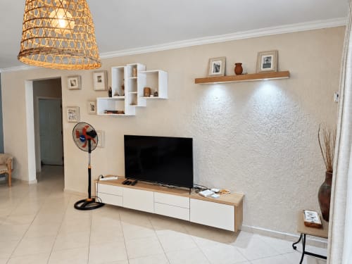 Modern living room at Gerards & Angel apartment in Flic en Flac with flat-screen TV, wooden shelving, and textured white