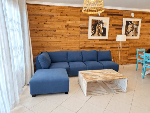 Modern living room with blue sectional sofa, wooden coffee table, and wood-paneled walls at Gerards & Angel apartment in Flic