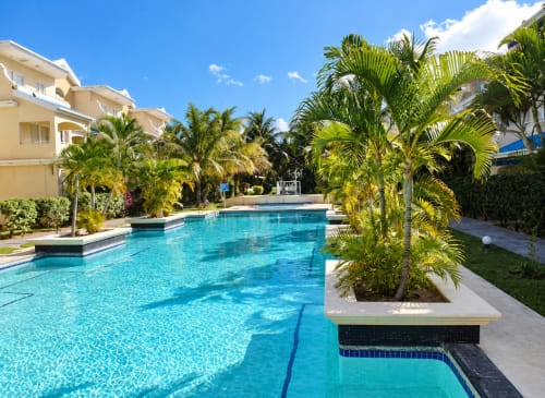 Crystal-clear swimming pool surrounded by palm trees at Gerards & Angel apartment in Flic en Flac, Mauritius