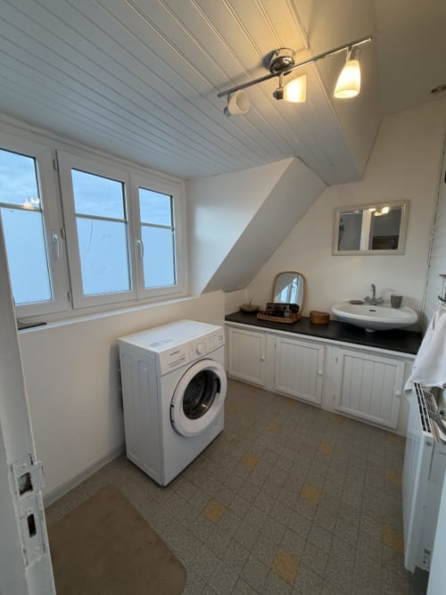 Buanderie moderne avec lave-linge, lavabo et rangements blancs au gîte Mon Week End A La Mer à Hautot-sur-Mer
