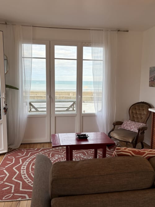 Salon de la maison de vacances en bord de mer avec vue sur la mer, portes-fenêtres et mobilier élégant
